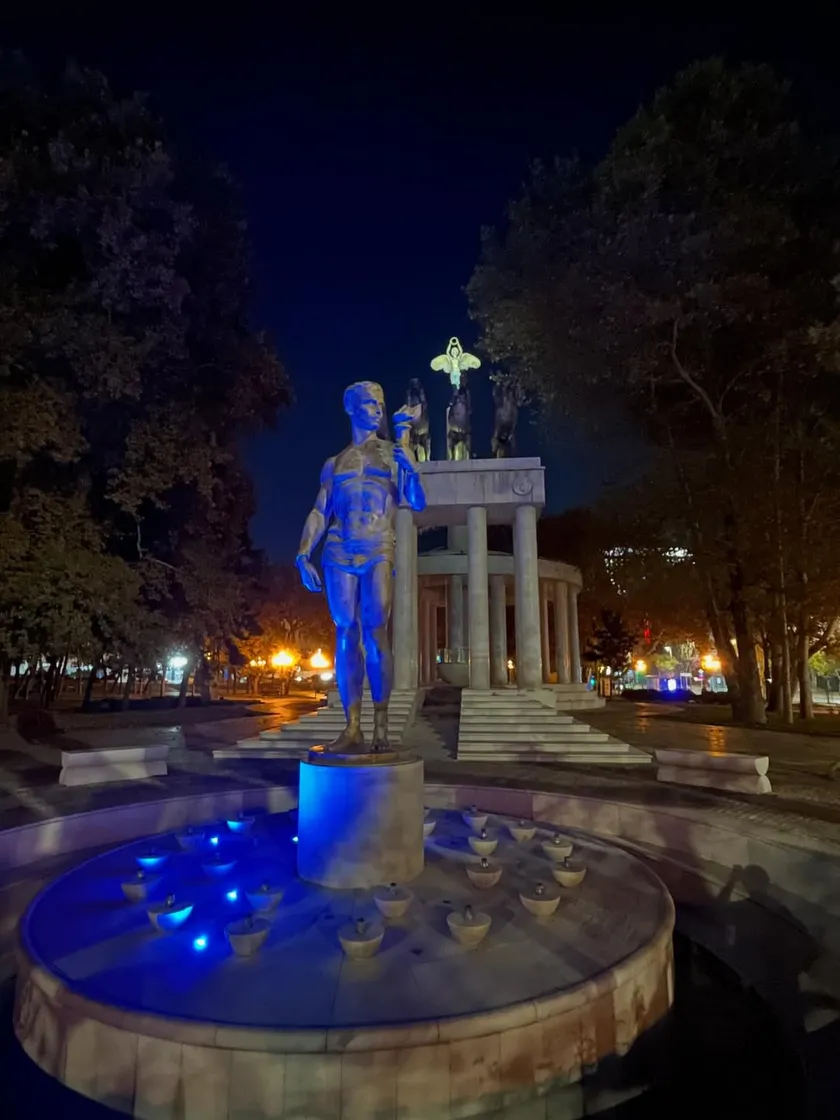 Illuminated fountain statue of a man in front of classical columns